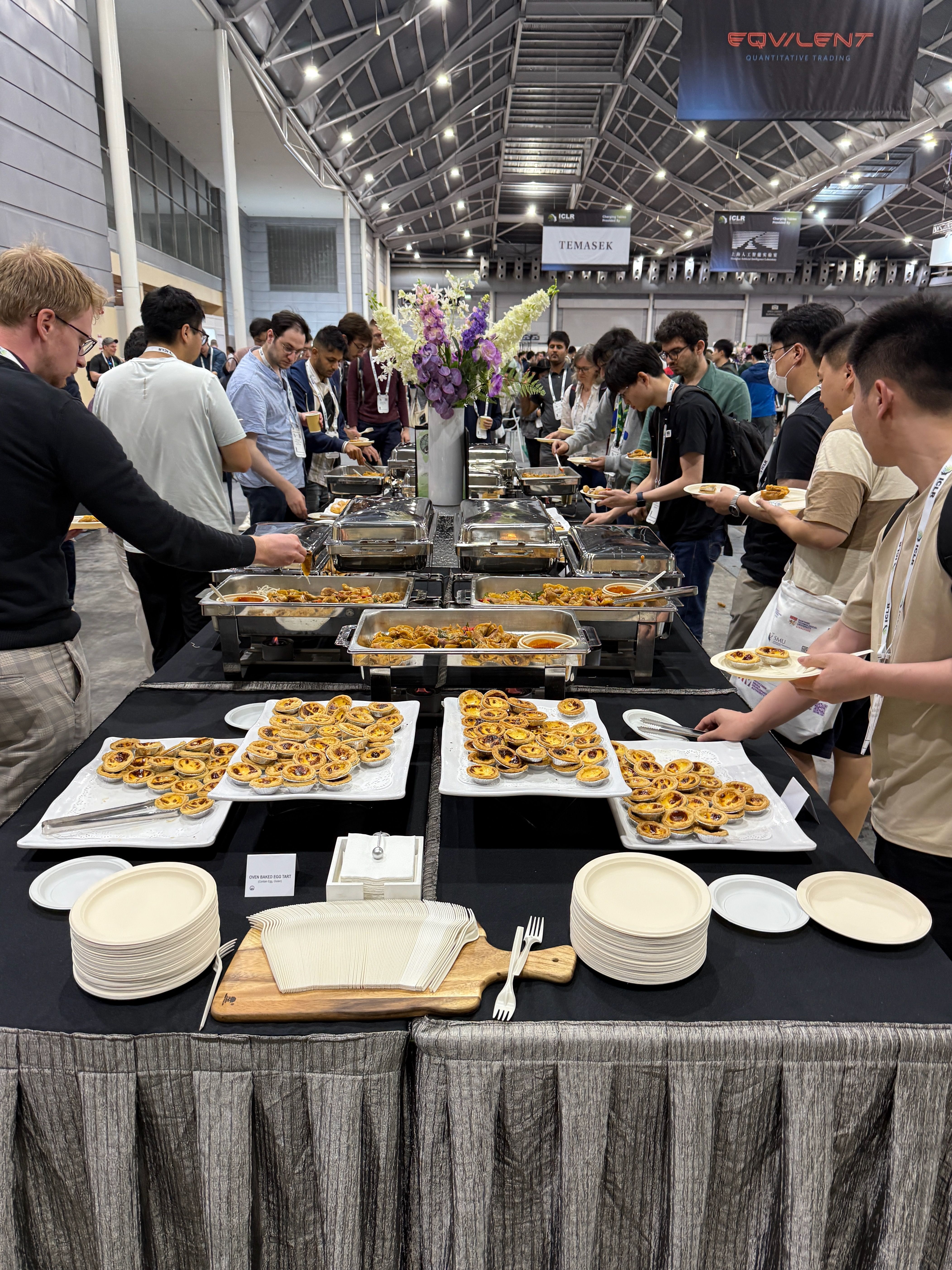 Around a dozen researchers line up at a long table stacked with pastries and other snacks. 