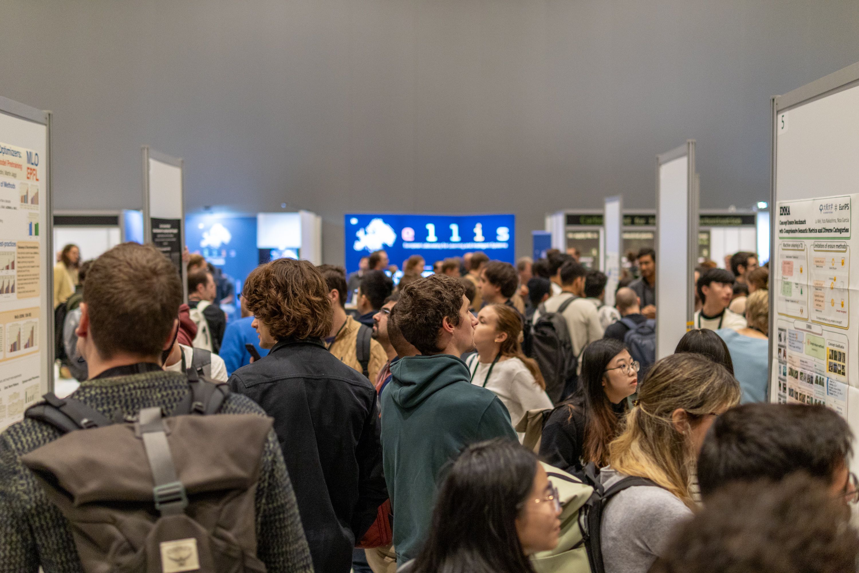 Dozens of people gather around posters presenting academic papers