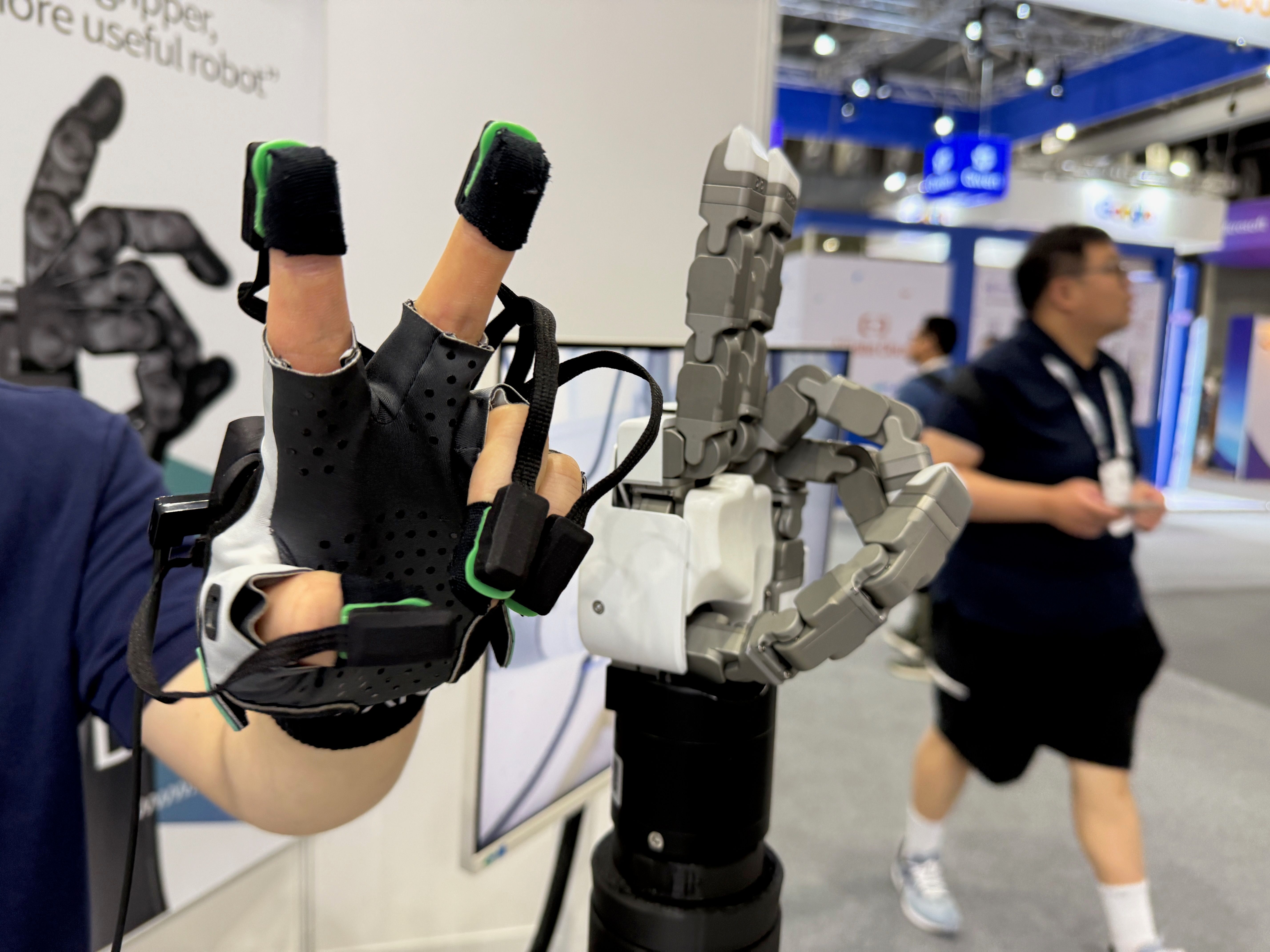 A close up photo of a human hand in a sensor glove making a peace sign. Next to the human hand, a robot hand performs the same gesture. 