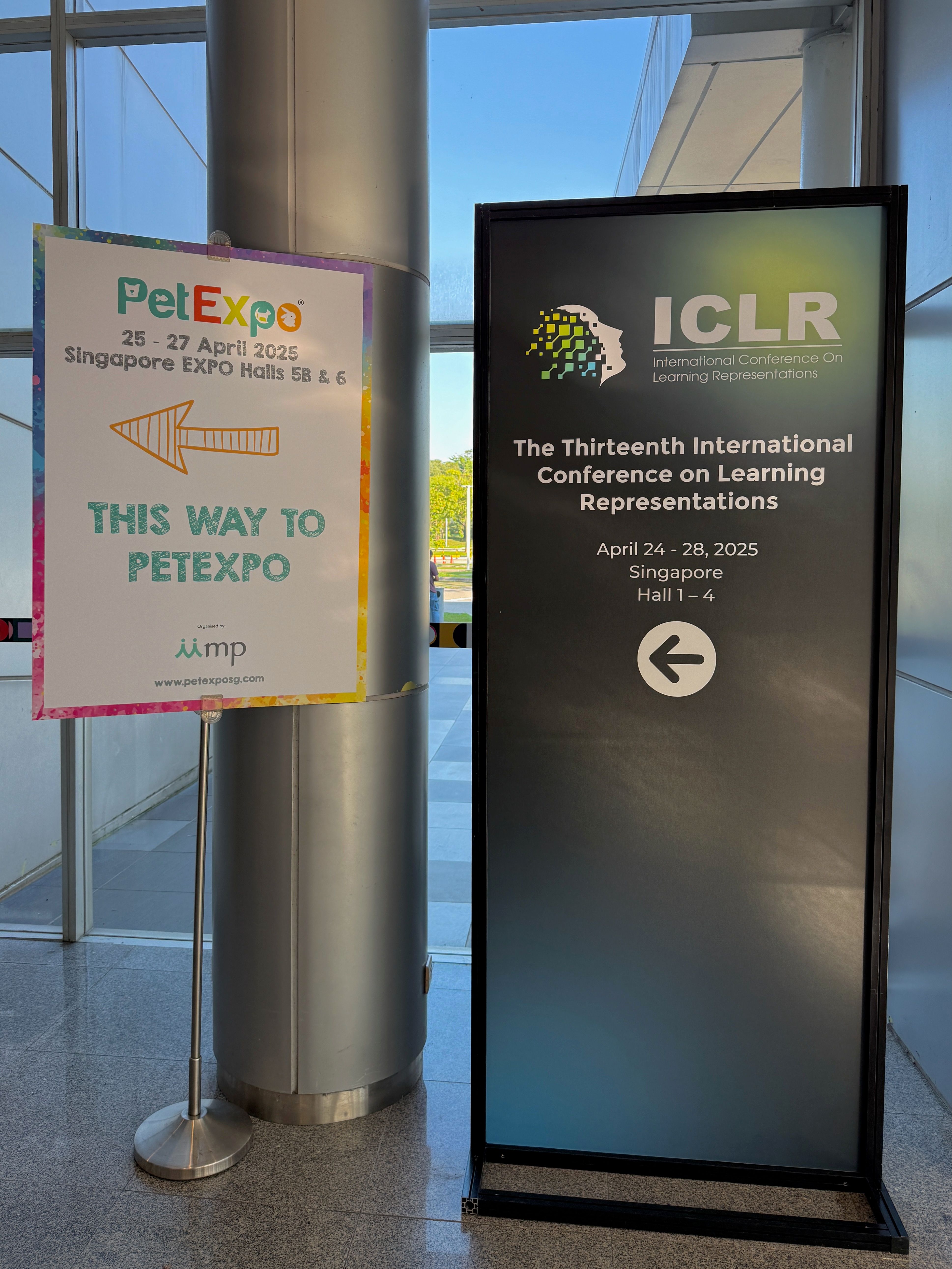 Two signs next to each other. One reads 'This way to РetExpo'. The other reads 'The Thirteenth International Conference on Learning Representations'. Both point left. 