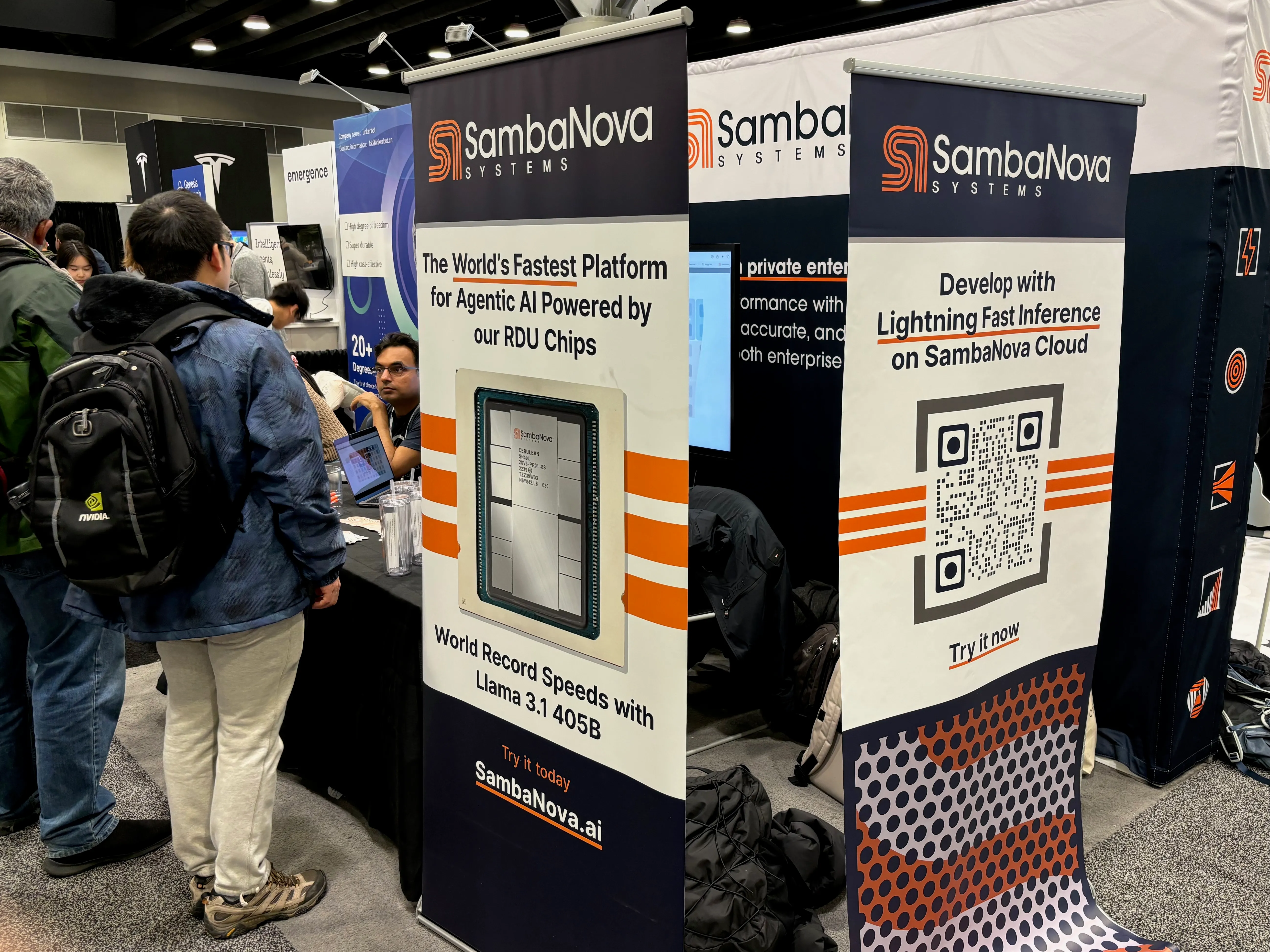 Photo of a sponsor booth at NeurIPS, with people gathered around talking to a person behind the booth. Poster in front of the booth
reads 'The World's Fastest Platform for Agentic Al Powered by our RDU Chips, World Record Speeds with Lama 3.1 405B,
Try it today, SambaNova.ai'